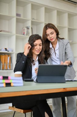 Portre, iki profesyonel ve zeki bin yıllık beyaz iş kadını iş kadını tablet ekranına bakıyor ve projelerini ofiste birlikte planlıyorlar.