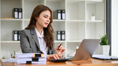 Profesyonel bin yıllık beyaz iş kadını ya da resmi iş elbisesi içindeki kadın muhasebeci görevlerine odaklanıyor, bilgisayardaki satış verilerini kontrol ediyor, ofiste çalışıyor..
