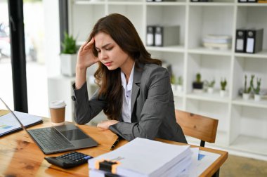 Masasında oturan stresli ve düşünceli genç beyaz iş kadını iş projesinin sonuçlarından dolayı üzgün ve memnuniyetsiz hissediyor, baş ağrısı ya da aşırı çalışma..