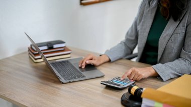 Masasında çalışan profesyonel Asyalı kadın avukat dizüstü bilgisayar ve hesap makinesi kullanıyor. kırpılmış resim