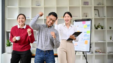 Bir grup Asyalı iş adamı ya da yeni başlayanlar ofiste birlikte başarılarını kutluyorlar..