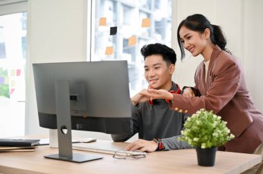 Profesyonel Asyalı kadın yönetici, erkek web geliştiricisine danışmanlık yapıyor ve onunla birlikte çalışıyor..