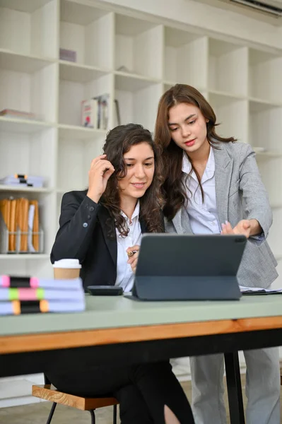 stock image Portrait, Two professional and smart millennial caucasian businesswomen in business suit looking at the tablet screen, checking and planning their project together in the office