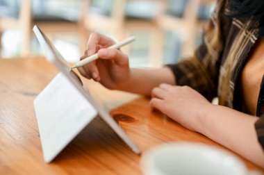 Yakın plan görüntü, Asyalı bir üniversite öğrencisi ya da serbest çalışan kafede otururken dijital tablet kullanarak çalışmalarını tasarlıyor..