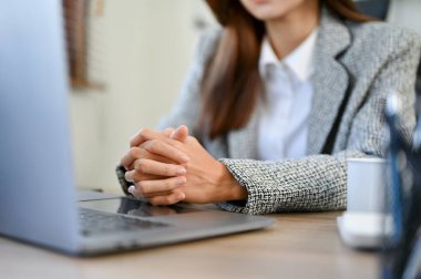 Profesyonel ve ciddi Asyalı iş kadını ya da bayan yönetici online bir toplantıya katılırken ellerini masaya kenetledi. Görüntüyü kapat