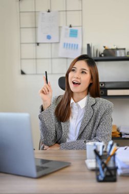 Portre, güzel Asyalı genç iş kadını ya da elinde kalem tutan ve yeni proje kampanyası hakkında yeni bir fikir üreten kadın ofis çalışanı..