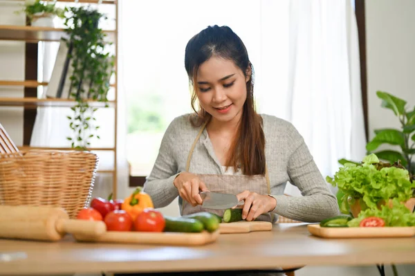 美丽的千年亚洲女性或家庭主妇在厨房里专心致志于切黄瓜以换取健康的沙拉碗 — 图库照片