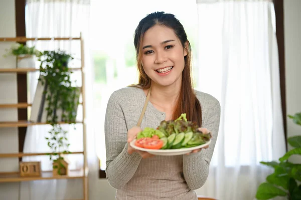 迷人而微笑的年轻亚洲女人穿着围裙 手里拿着一盘新鲜的有机绿色沙拉 健康食品和生活方式概念 — 图库照片