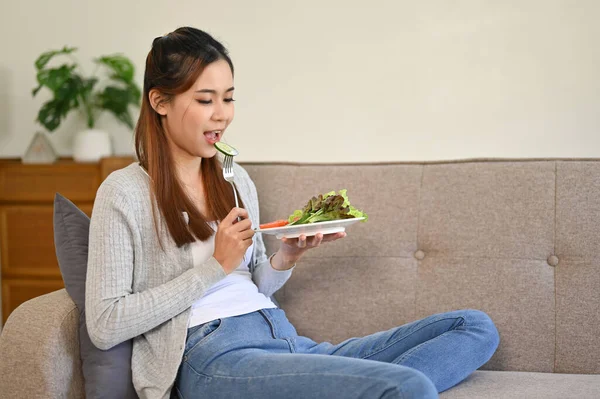 健康漂亮的亚洲女孩一边吃着健康的沙拉 一边在客厅里放松 健康和幸福生活方式概念 — 图库照片
