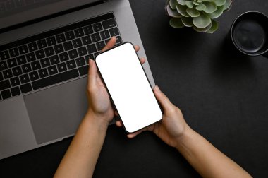 Üst Manzara, bir akıllı telefon beyaz ekran modeli modern siyah ofis masasında bir kadının elinde..