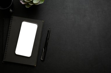 Akıllı telefon beyaz ekran modeli, not defteri, kalem ve kopya alanı ile modern siyah masa üstü çalışma alanı siyah arkaplanda metninizi göstermek için. Üst görünüm, düz uzanma