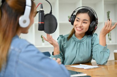 Çekici ve çekici Asyalı bayan radyo sunucusu stüdyodaki özel konuğu ile konuşmaktan ve röportaj yapmaktan hoşlanıyor..
