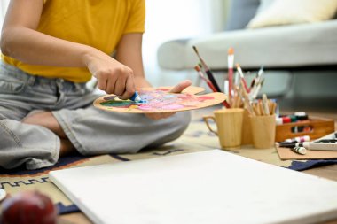 Bir bayan ressam ya da öğrenci oturma odasında elinde paletle oturur, sanat eserleri için akrilik rengini hazırlar ya da karıştırır, evde sanat ödevlerini yapar. Yakın çekim.