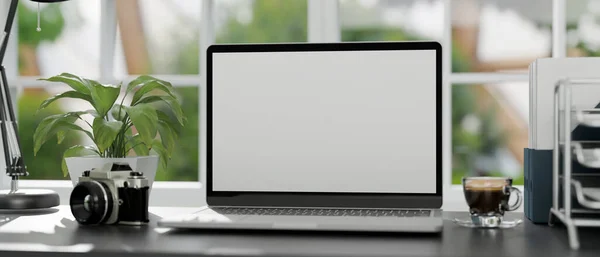 オフィスデスクワークスペースノートパソコンのホワイトスクリーンモックアップ コーヒーカップ カメラ オフィス用品がぼやけた背景にクローズアップされます 3Dレンダリング 3Dイラスト — ストック写真