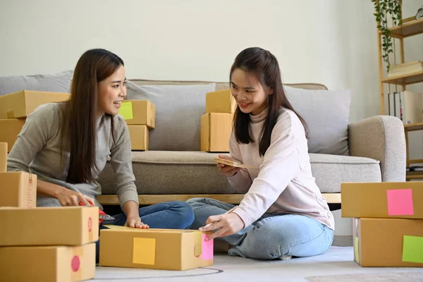 stock image Two successful young Asian female online small business owners or SME startup entrepreneurs working at home, enjoys preparing delivery packages together.