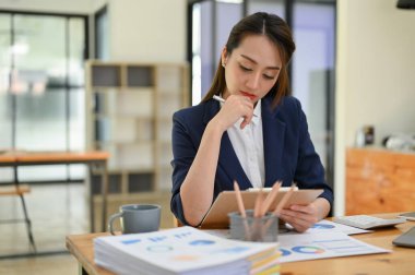 Profesyonel Asyalı iş kadını ya da finansal raporuna yoğunlaşan ve masasında çalışan kadın finans müdürü..