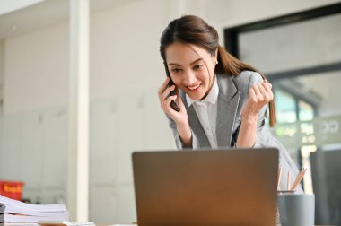 Çekici ve çekici Asyalı genç bayan müşteri yöneticisi ya da pazarlama asistanı ortağıyla telefonda iş yapıyor, telefon görüşmesinde iyi anlaşmalar yapıyor..