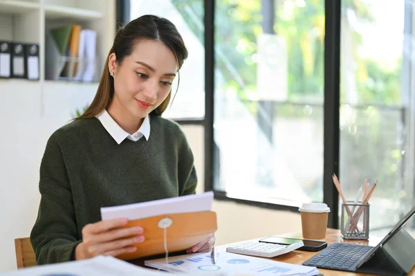 stock image Beautiful millennial Asian businesswoman or female assistant opening the letter or document for reading, working at her desk.