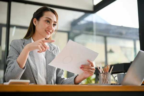 stock image Attractive young Asian businesswoman holding a paper or document, working at her office desk.