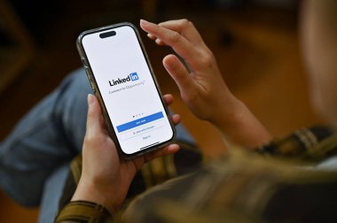 Chiang Mai, Tayland - 24 Kasım 2022: Akıllı telefonunu kullanan bir kadın, ekranda Linkedin logosu olan bir akıllı telefon tutuyor. İş ve staj platformu