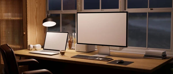 现代简朴舒适的夜间工作空间 配有电脑和笔记本电脑的白色屏幕模型 台灯的灯光和木制桌子上的装饰 3D渲染 3D说明 — 图库照片