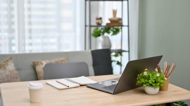 Laptop bilgisayarı, kırtasiye malzemesi, masanın üzerinde bir fincan kahve ve dekor olan modern şehir ofis çalışma alanı..