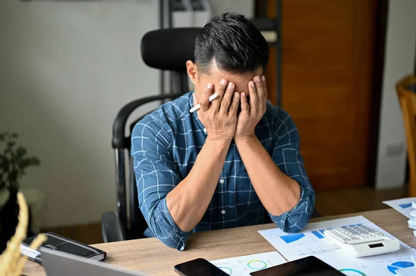 Stressed Asian businessman or male business startup entrepreneur suffering from his anxiety, feeling upset with his work performance. failure, exhausted, crying, no work passion.