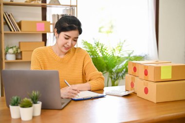 Çekici Asyalı kadın serbest yazar ya da evindeki masasında çalışan küçük bir online dükkan sahibi. E-ticaret iş konsepti