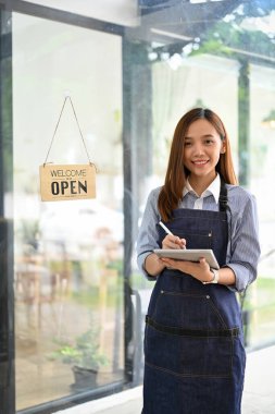 Portre, güzel ve çekici Asyalı bayan barmen ya da önlüklü garson kafenin girişinde portatif tabletiyle duruyor..