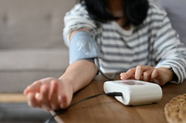 Tansiyonunu ve kalp atışlarını evde tek başına kontrol eden Asyalı bir kadın. Sağlık ve tıbbi konsept. kırpılmış atış