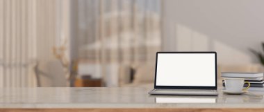 Arka planda bulanık modern oturma odasının üzerinde dizüstü bilgisayar, beyaz ekran maketi, kahve fincanı, kitap ve kopya alanı olan lüks çalışma alanı masası. 3d görüntüleme, 3d illüstrasyon