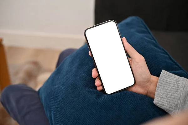 stock image Above view, A man hand's holding a smartphone white screen mockup over his lap. Technology concept