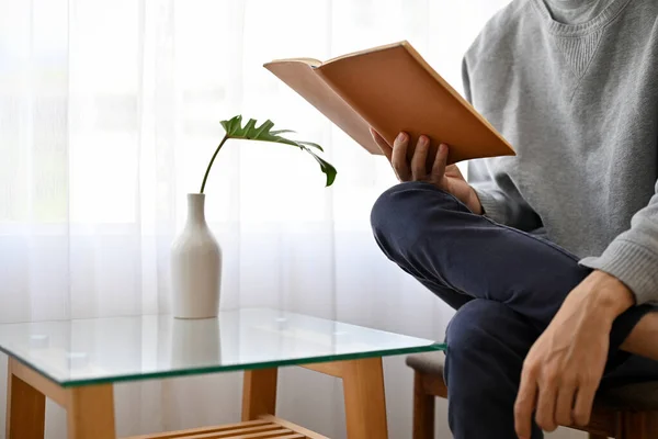 stock image A handsome and casual young Asian man reading a book while relaxing in the coffee shop. cropped image