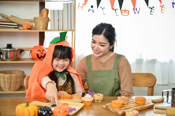 快乐的家庭观念 一个可爱的亚洲小女孩喜欢和妈妈一起在厨房做和装饰万圣节纸杯蛋糕 — 图库照片