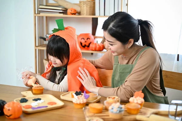 可爱的亚洲妈妈在厨房教她的小女儿做万圣节蛋糕 快乐家庭和万圣节的概念 — 图库照片