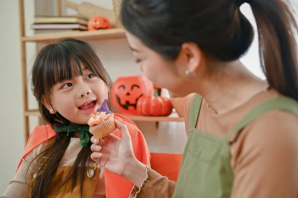 할로윈 의상을 장난스럽고 귀여운 아시아 소녀가 엄마와 부엌에서 케익을 이미지 — 스톡 사진