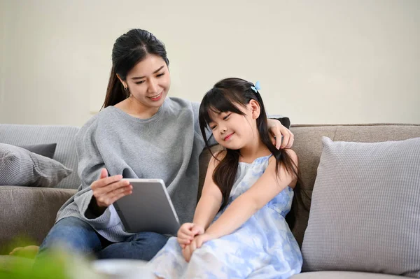 아시아 어머니 거실에서 휴식을 취하는 동안어린 태블릿으로 아이의 만화를 있습니다 — 스톡 사진