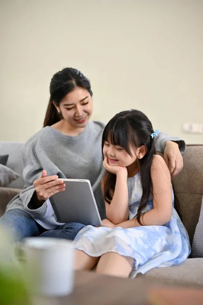 초상화 귀여운 아시아 소녀는 거실에서 엄마와 태블릿을 인터넷에서 재미있는 비디오를 — 스톡 사진