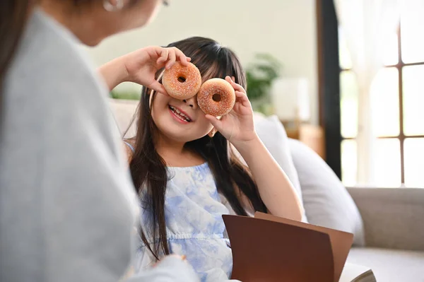 도넛을 랑놀고 거실에서 시간을 보내는 장난기많고 귀여운 아시아 — 스톡 사진