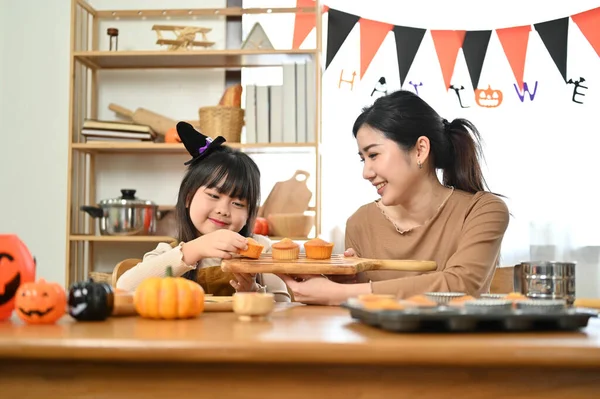 漂亮而快乐的身穿华丽服装的亚洲小女孩 和妈妈一起为万圣节派对做万圣节蛋糕 — 图库照片