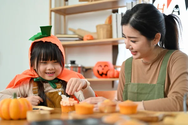 快乐的家庭观念 穿着万圣节服装的活泼可爱的亚洲女孩喜欢和妈妈一起做万圣节纸杯蛋糕 — 图库照片