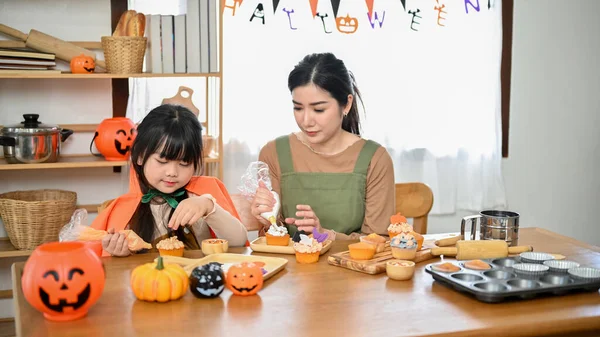 一个可爱的年轻亚洲女孩正在厨房里和妈妈一起装饰她的万圣节蛋糕 快乐的家庭观念 — 图库照片