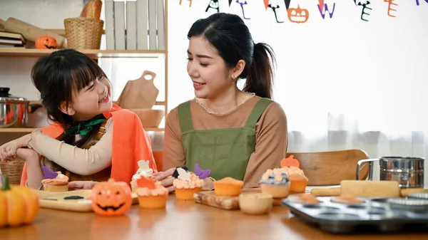 在家里做万圣节纸杯蛋糕的时候 快乐又顽皮的年轻亚洲女孩一边笑一边和妈妈一起玩 — 图库照片
