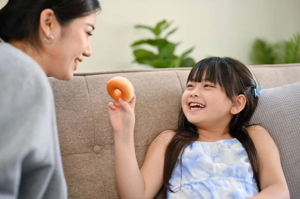 거실에서 쉬면서 엄마에게 맛있는 도넛을 먹이고 귀여운 아시아 — 스톡 사진