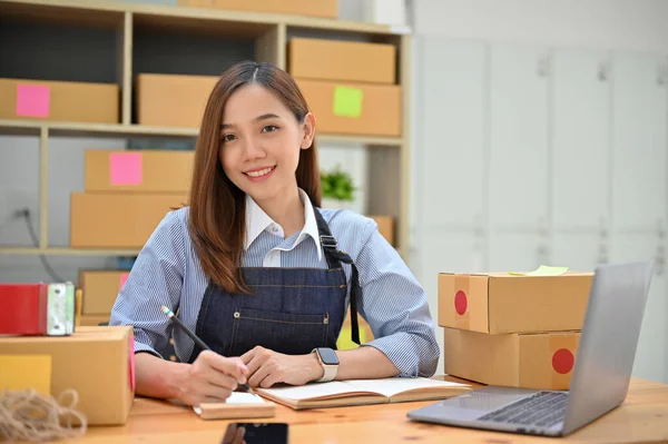 美丽而迷人的年轻亚洲女企业家或小企业经营者在她的储物柜和包装室的工作台上工作 — 图库照片