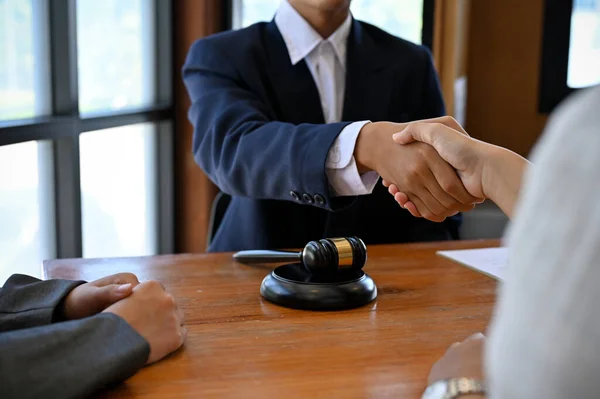 A professional male lawyer in a formal suit shakes hands with his client after making the deal and being hired to manage his lawsuit. cropped image