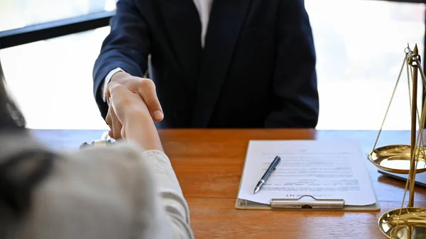 A business lawyer in the meeting with his client in the office of a law firm. Shaking hands for successful agreement. close-up image