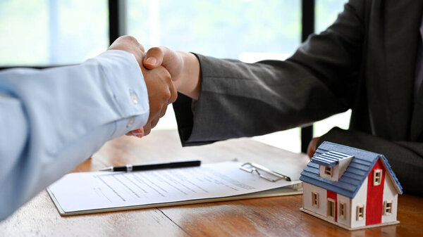 Real estate agent or realtor shakes hands with her client after making the deal in the office. cropped shot