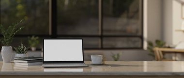 Çalışma alanı masa üstü dizüstü bilgisayar beyaz ekran modeli, kitaplar, kahve fincanı, dekor bitkisi ve arka plandaki bulanık oturma odasının üzerine kopyalama alanı. 3d görüntüleme, 3d illüstrasyon