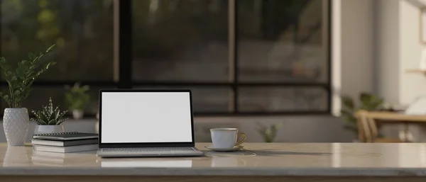 stock image Workspace tabletop with laptop computer white screen mockup, books, coffee cup, decor plant and copy space over blurred living room in the background. 3d render, 3d illustration